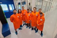 Dr inż. Arkadiusz Gertych (pierwszy z lewej) w towarzystwie młodych fizyków. W tle — pomieszczenie z reaktorem MBE (molecular beam epitaxy)
